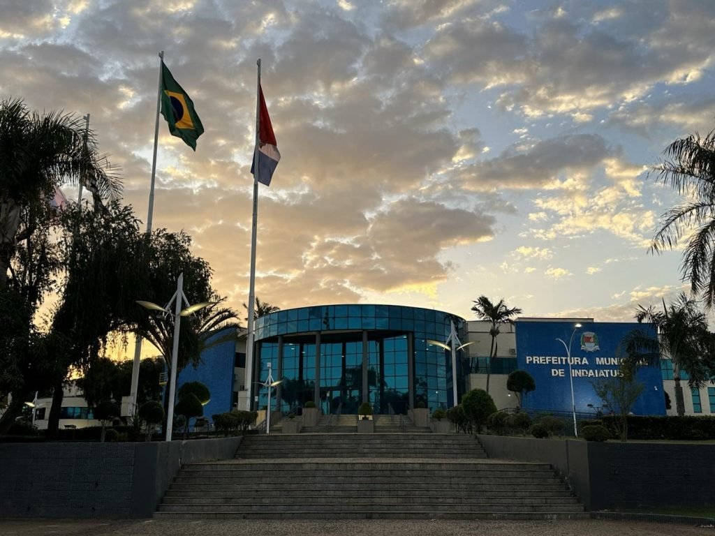 Fachada da Prefeitura de Indaiatuba com bandeiras e céu azul, representando o concurso público 2025